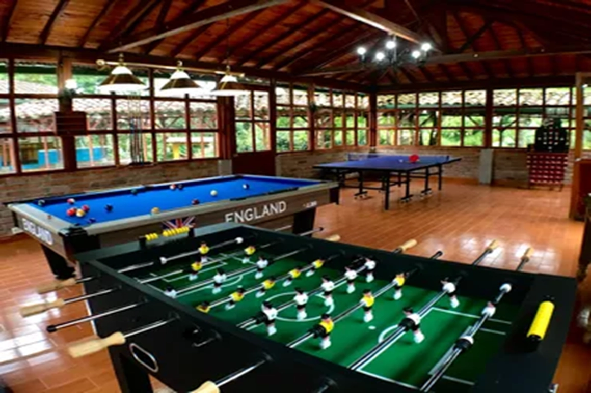 salon de juegos del hotel con mesas de billar, futbolin y mesa de ping pong